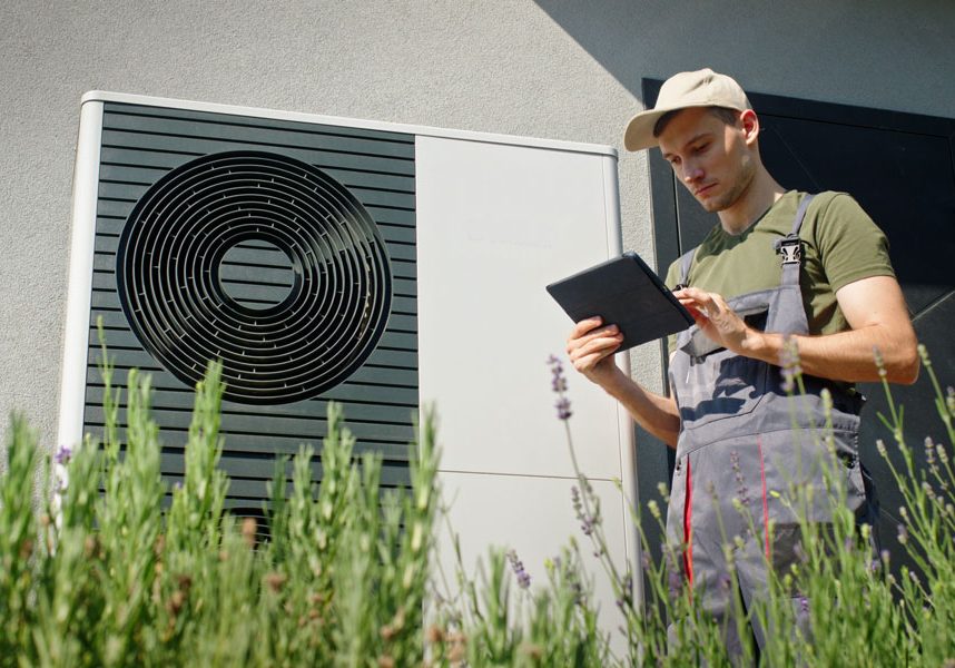 HVAC technician using a digital tablet to manage heat pump system data.